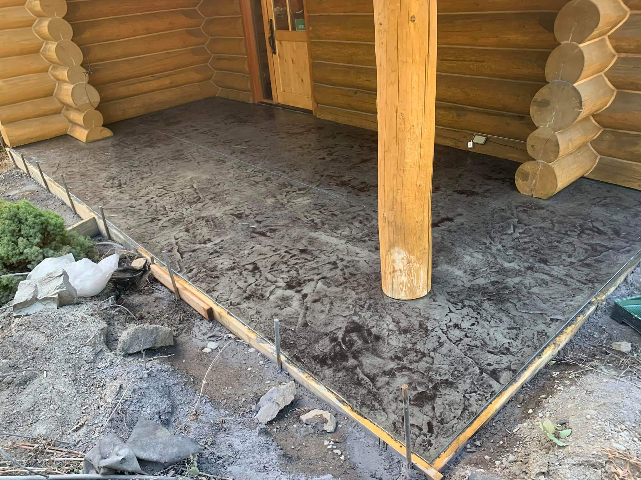 A log house's front patio showing a grey stamped concrete finish.